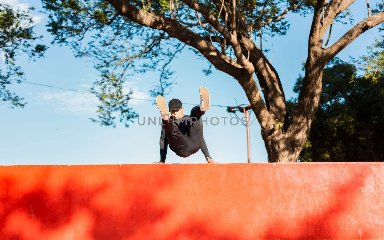 Guy doing wall jump parkour. Young man doing jumping parkour at sunset. Artistic image of man doing parkour