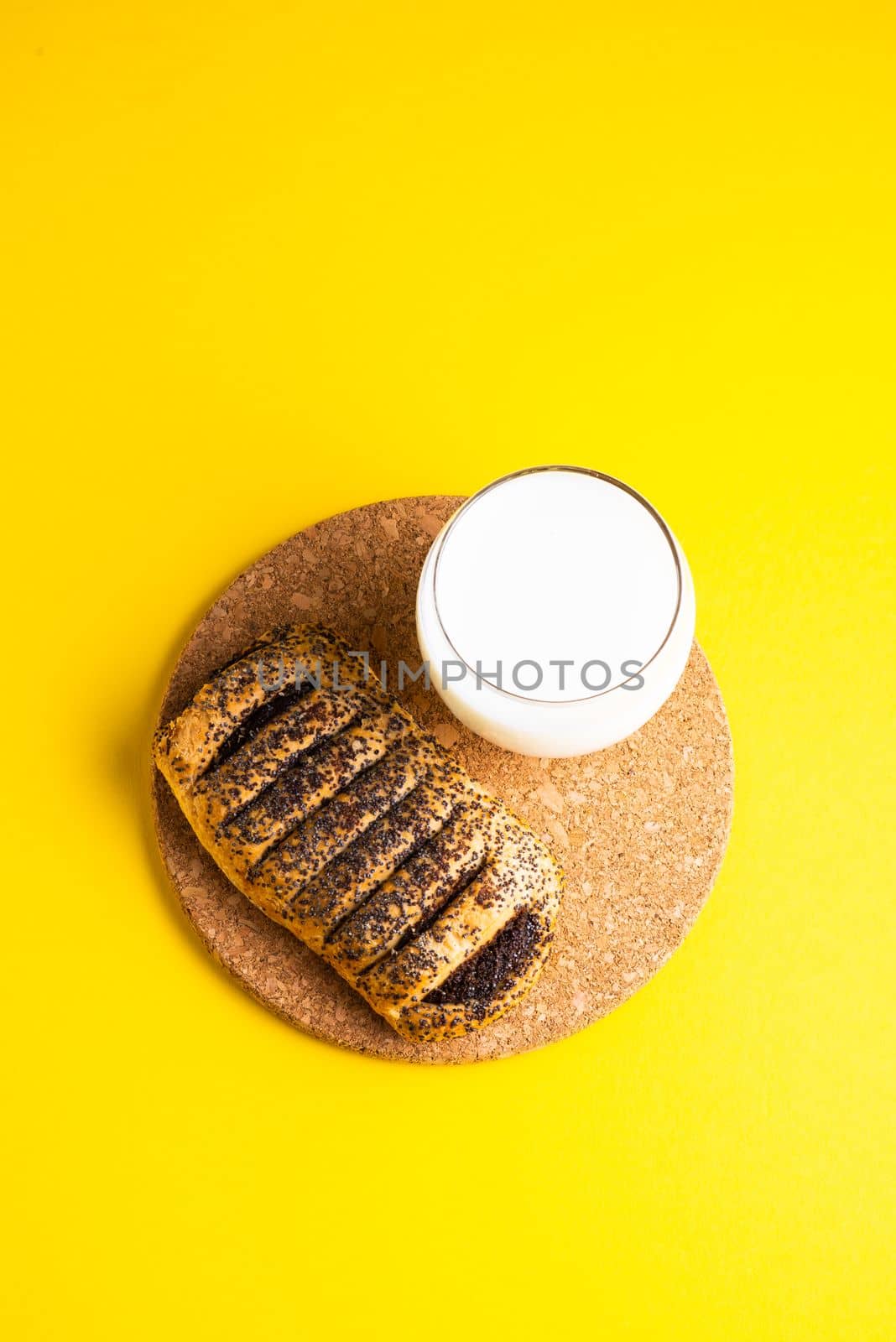 Breakfast bread and cup of milk on yellow and blue background
