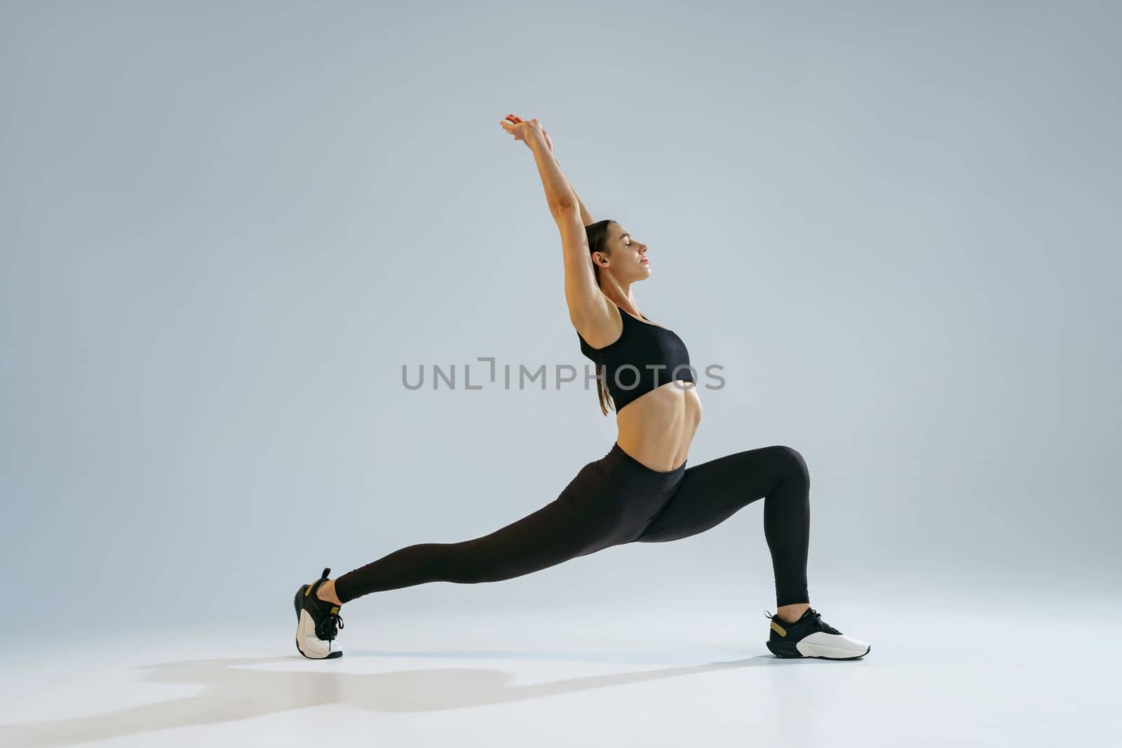 Flexible woman doing stretching exercises on studio background. Healthy lifestyle by Yaroslav_astakhov