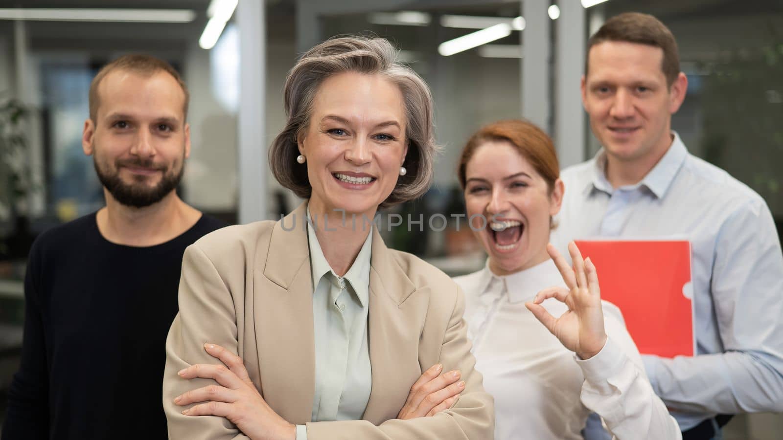 Portrait of four office workers. A gray-haired mature woman, a Caucasian man, a bearded man and a red-haired woman