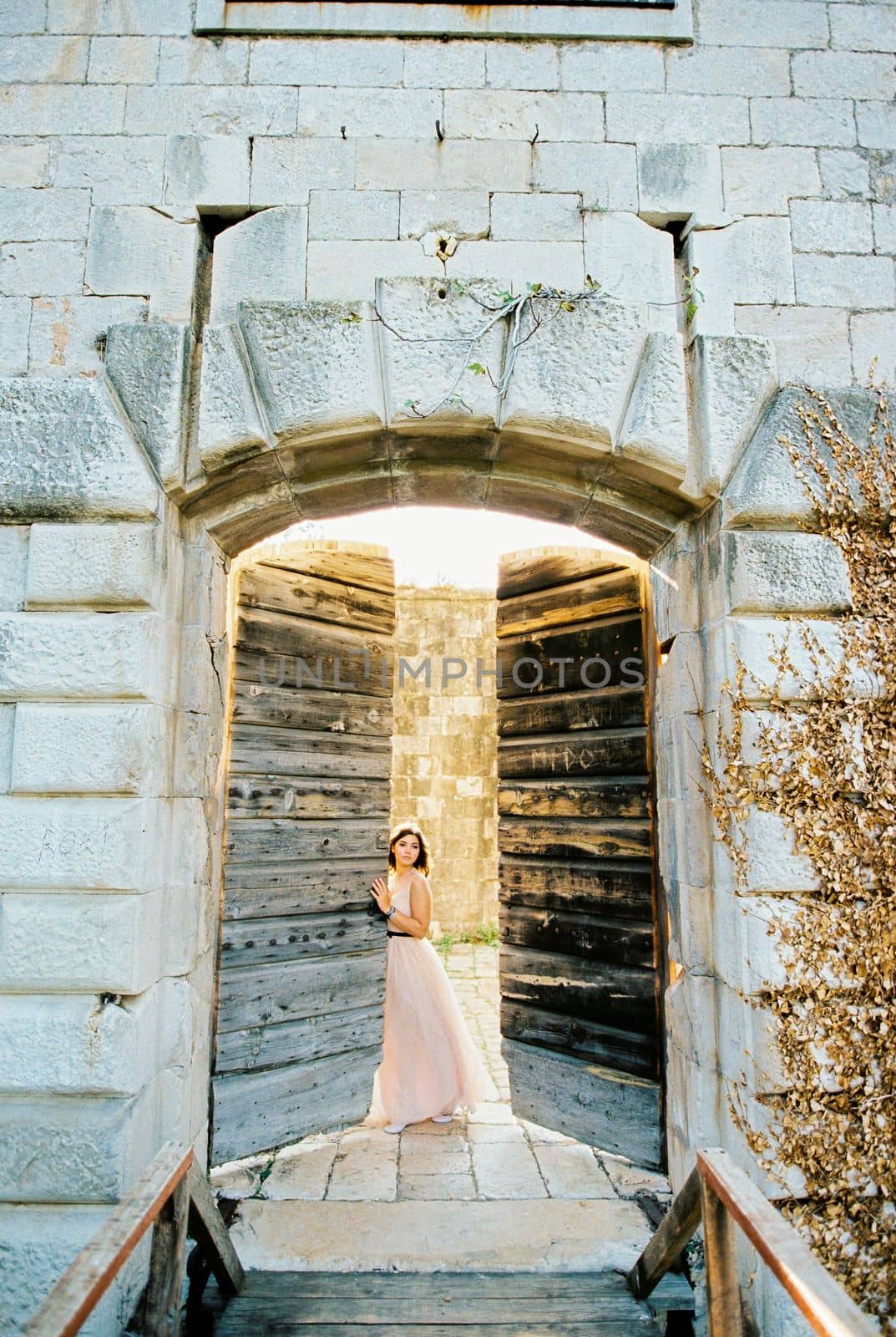 Bride opens the shabby old wooden door of the stone fortress. High quality photo