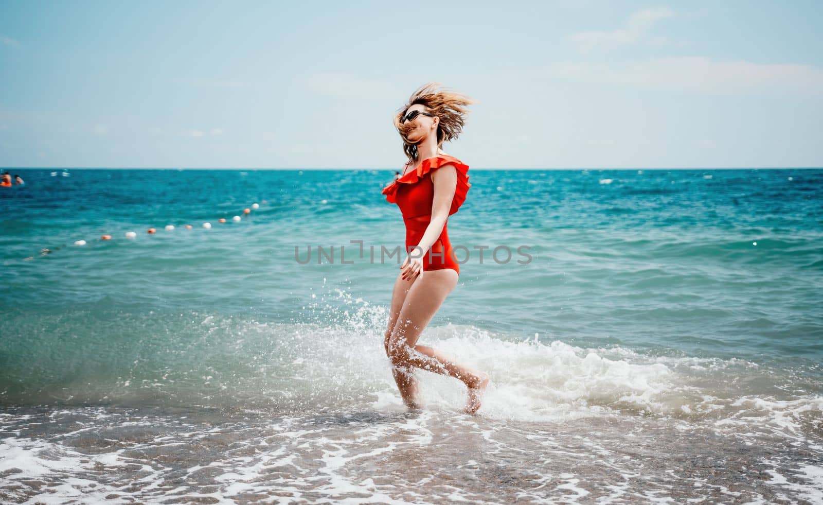 Young happy woman walks carefree on the seaside. Happy lady in red bikini. Portrait beautiful young woman relax smile around beach sea ocean in holiday vacation travel trip.