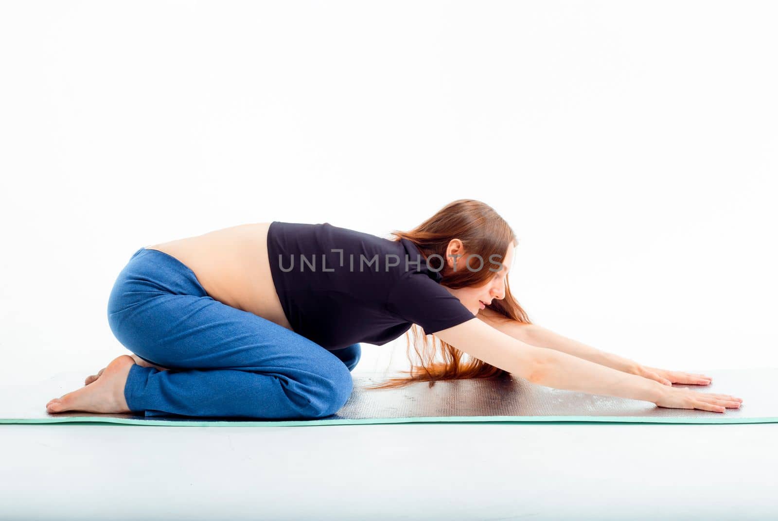 Pleasant pregnant woman posing in profile and trying yoga Young happy expectant relaxing, thinking about her baby and enjoying her future life. Motherhood, pregnancy, yoga concept. child's pose