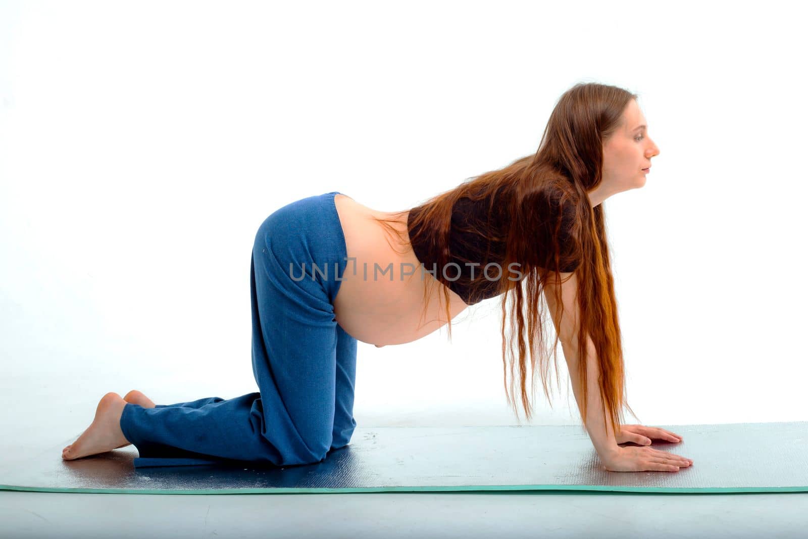 Pleasant pregnant woman posing in profile and trying yoga Young happy expectant relaxing, thinking about her baby and enjoying her future life. Motherhood, pregnancy, yoga concept.
