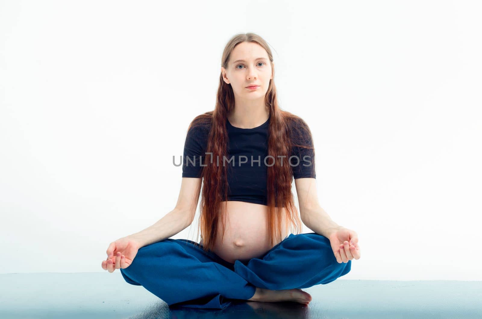 Pleasant pregnant woman posing in profile and trying yoga Young happy expectant relaxing, thinking about her baby and enjoying her future life. Motherhood, pregnancy, yoga concept, lotus position.