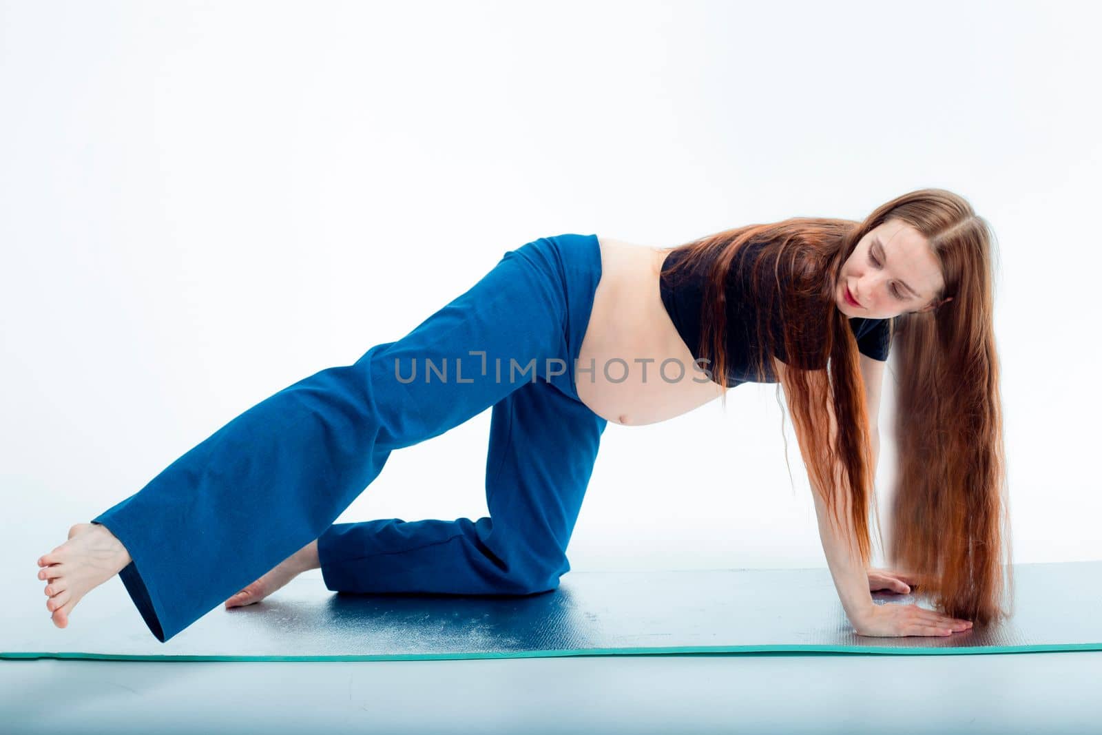 Pleasant pregnant woman posing in profile and trying yoga Young happy expectant relaxing, thinking about her baby and enjoying her future life. Motherhood, pregnancy, yoga concept.