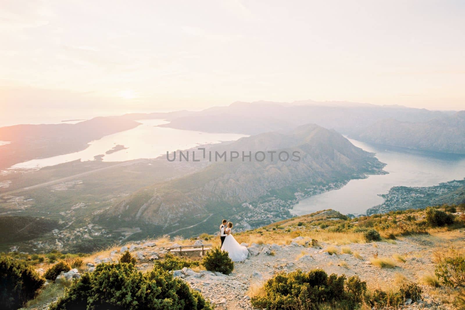 Bride and groom are standing on Mount Lovcen with a panorama of the Bay of Kotor. Montenegro. High quality photo