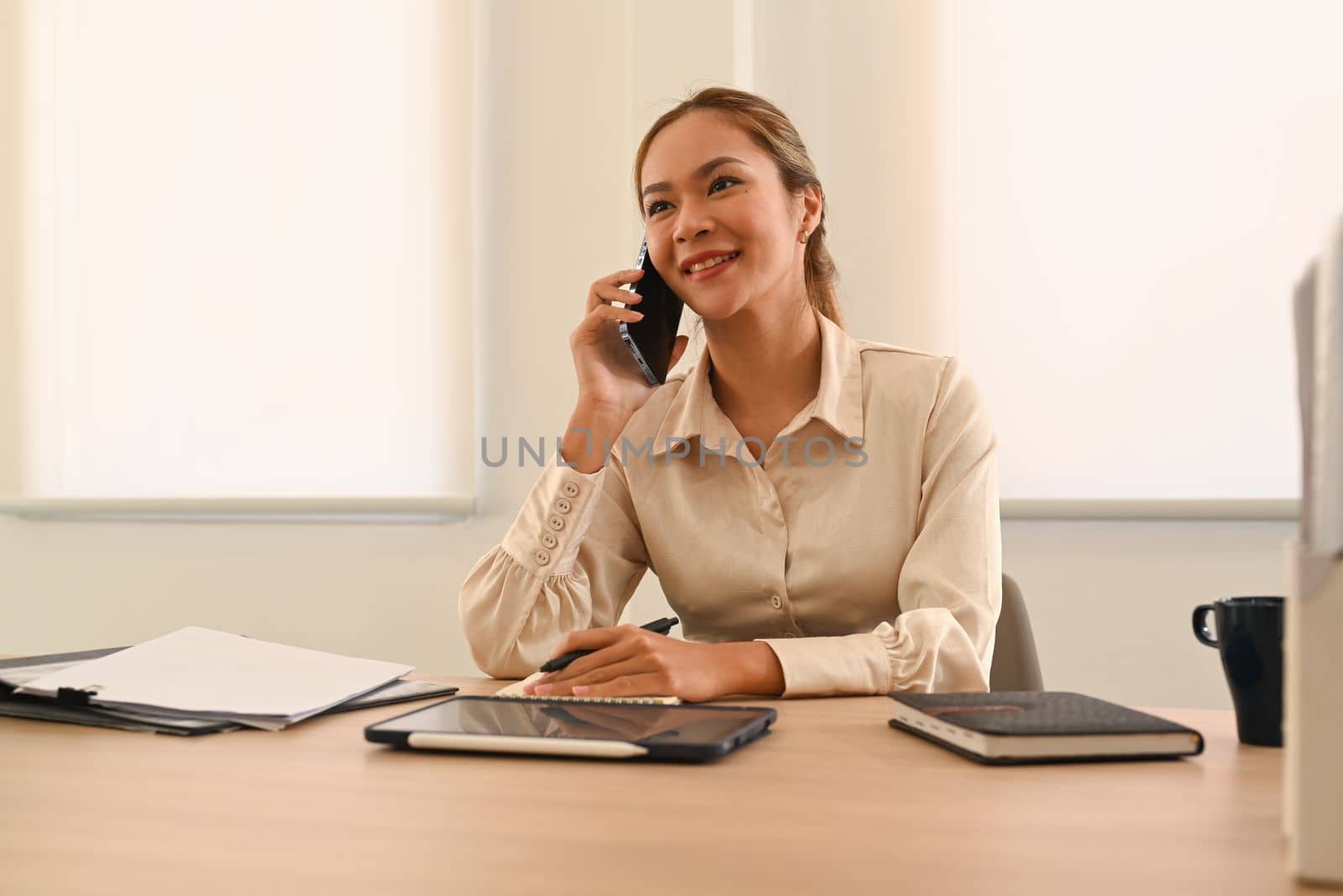 Portrait of confident businesswoman having pleasant mobile phone conversation with client by prathanchorruangsak