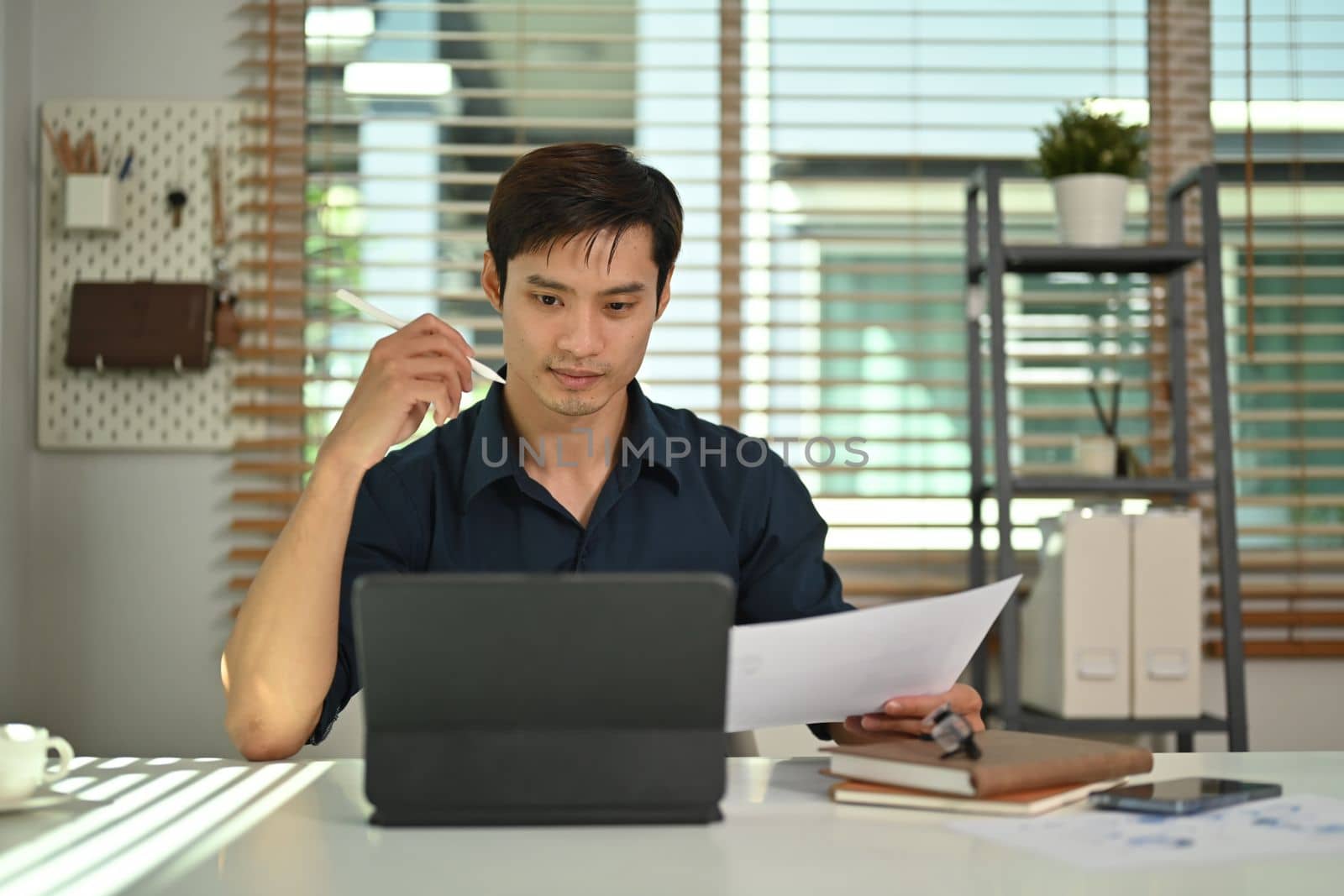 Focused millennial watching online webinar or seminar on laptop while working at home office. Remote job and lifestyle concept by prathanchorruangsak