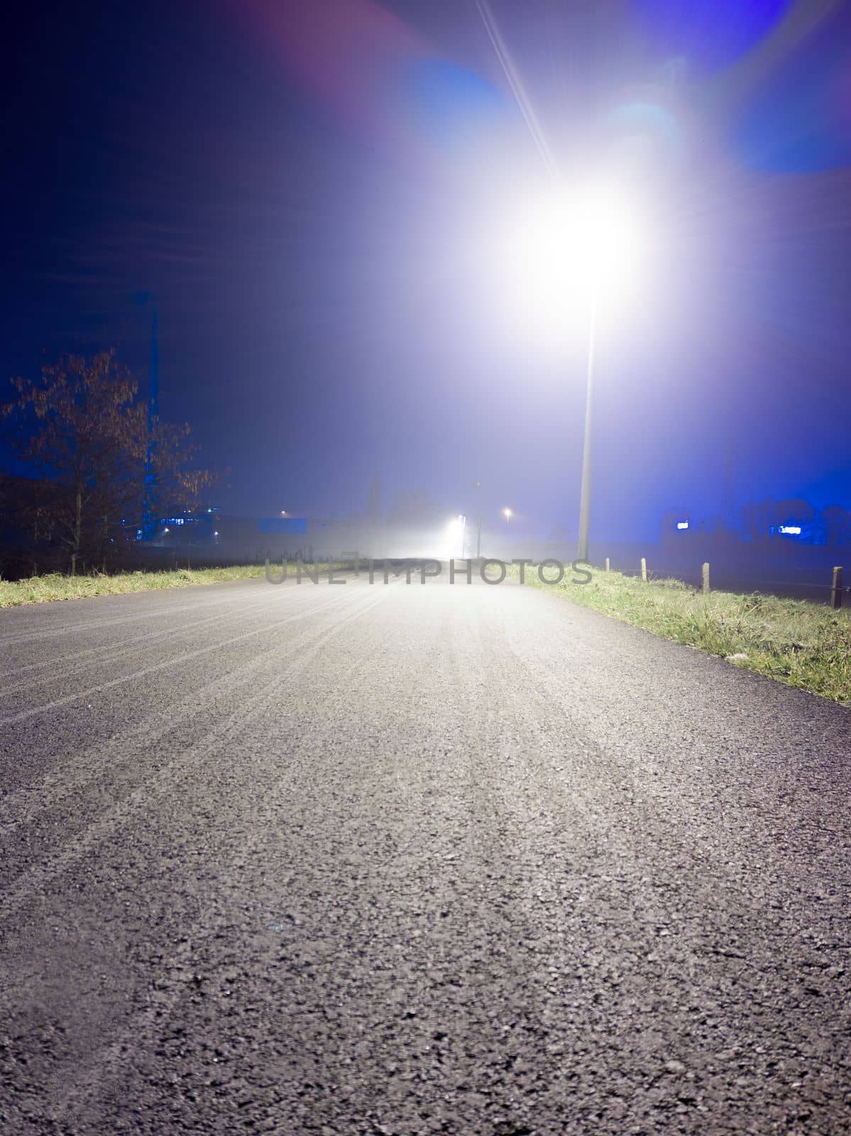 low angle view on a empty bicyclepath at night with a lighting streetlight and lensflare