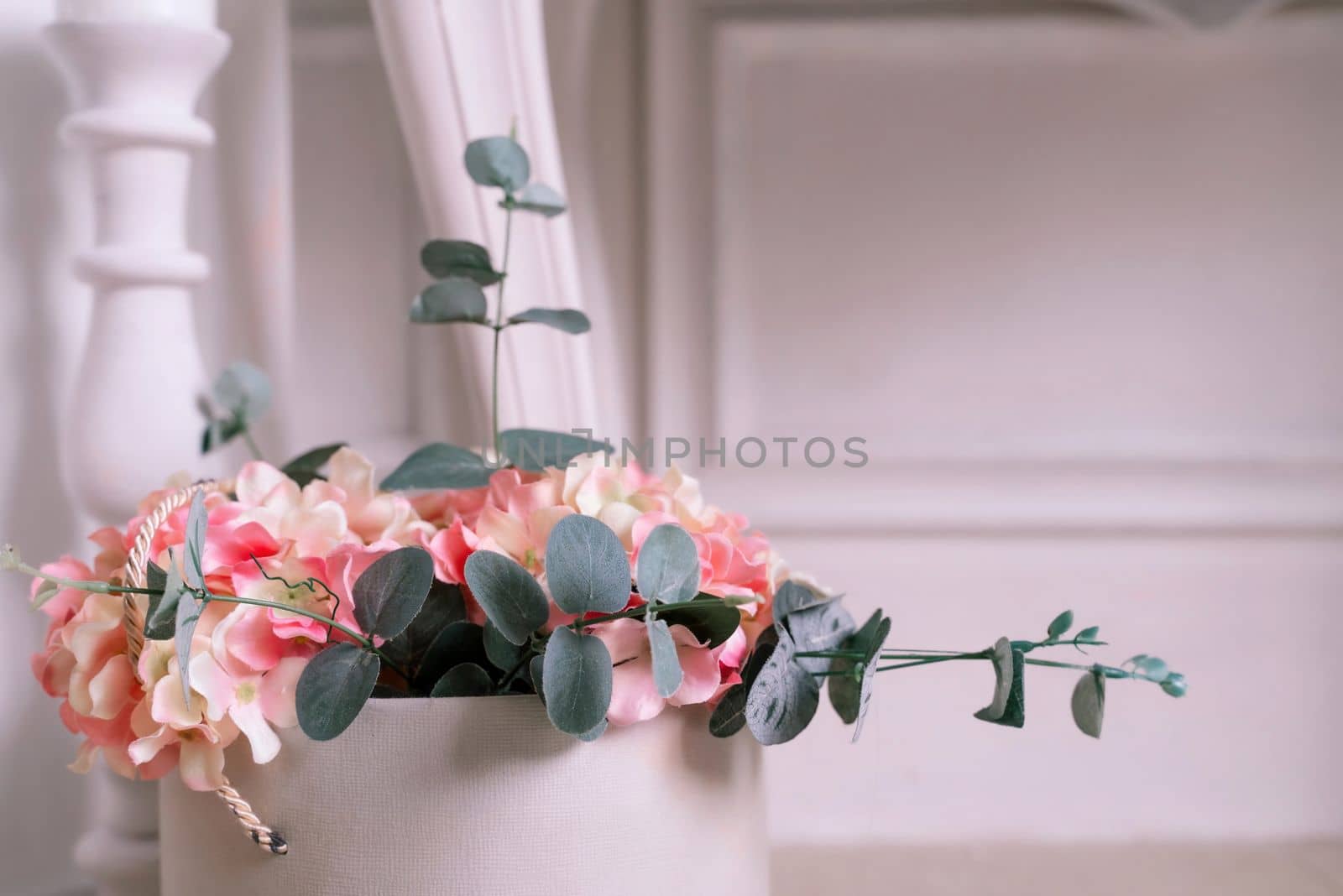 Hydrangea eucalyptus flowers bouquet in white box on white interior background.