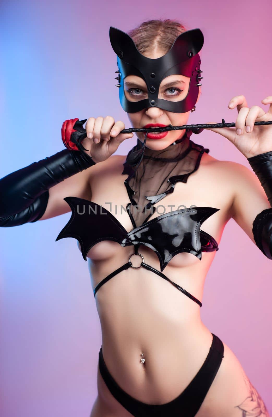Sexy girl in bdsm underwear leather mask and leather rose for bdsm games costume for sex games on pink bright background copy paste