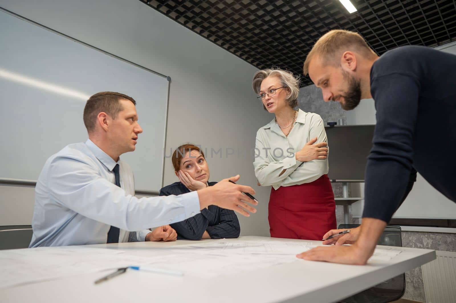 The female boss evaluates the work of subordinates. Designers engineers at a meeting