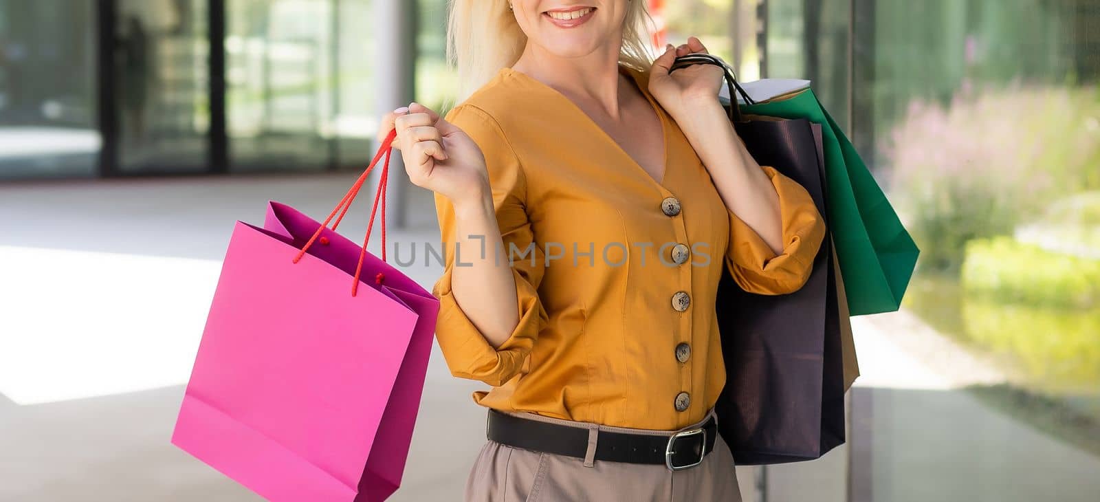 Happy woman holding shopping bags and smiling at the mall by Andelov13