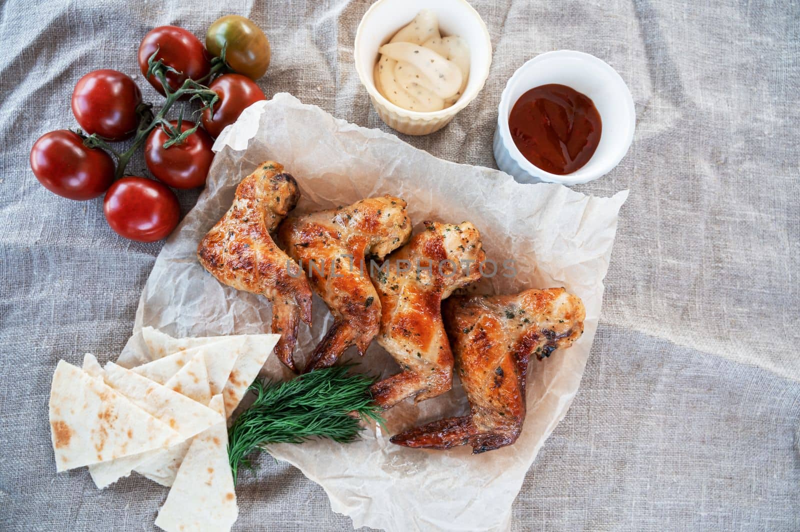 Ready spicy grilled chicken wings with greens and tomato. Summer rest concept