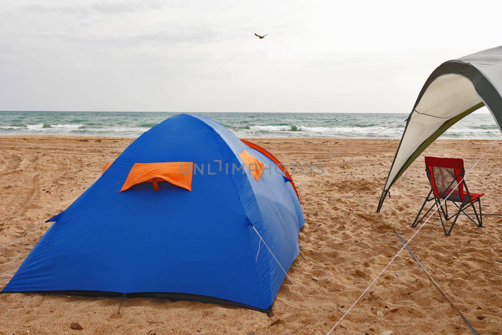 Camping by the sea with a tent, an awning and a sun lounger.