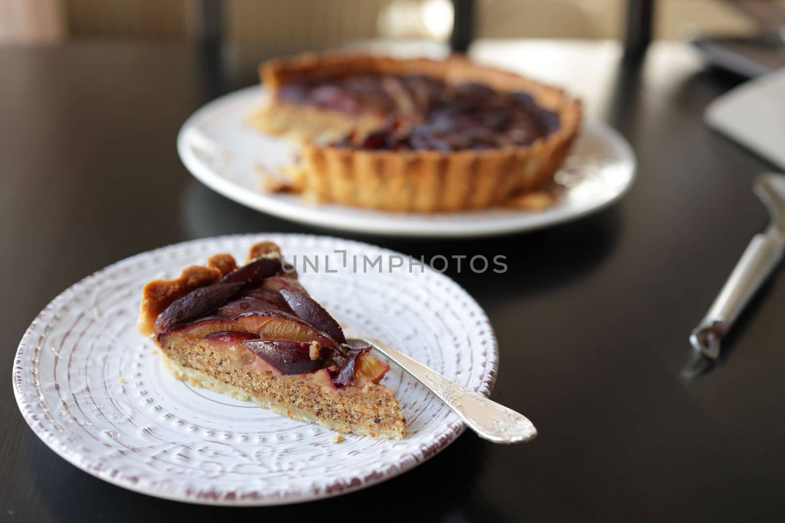 piece of plum and almond tart with frangipane on a white plate. selective focus by Proxima13