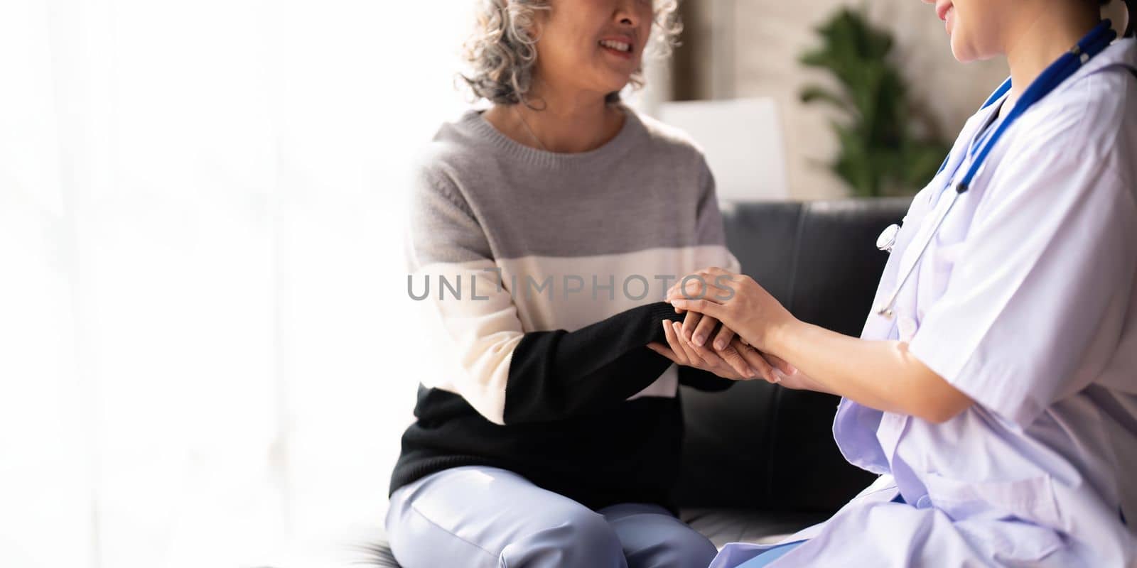 Home caregiver and senior woman holding hands. Professional Elderly Care. Professional care for elderly at nursing homes. Nurse holding hand of senior woman in rest home.