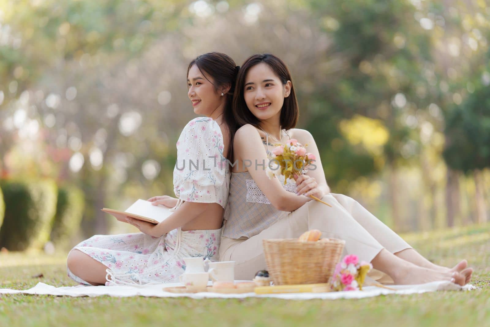 Beautiful woman and friend having picnic on sunny spring day in outdoor park. Valentine and LGBT concept. by itchaznong