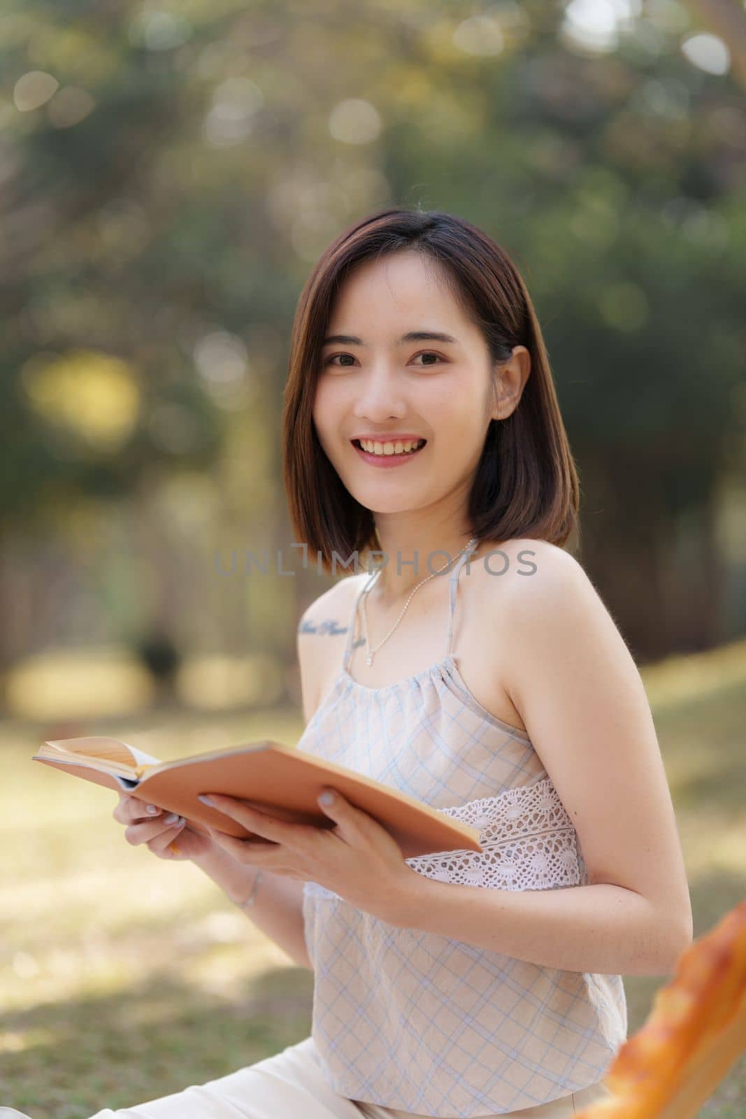 Young asian woman reading a book on picnic at outdoor park