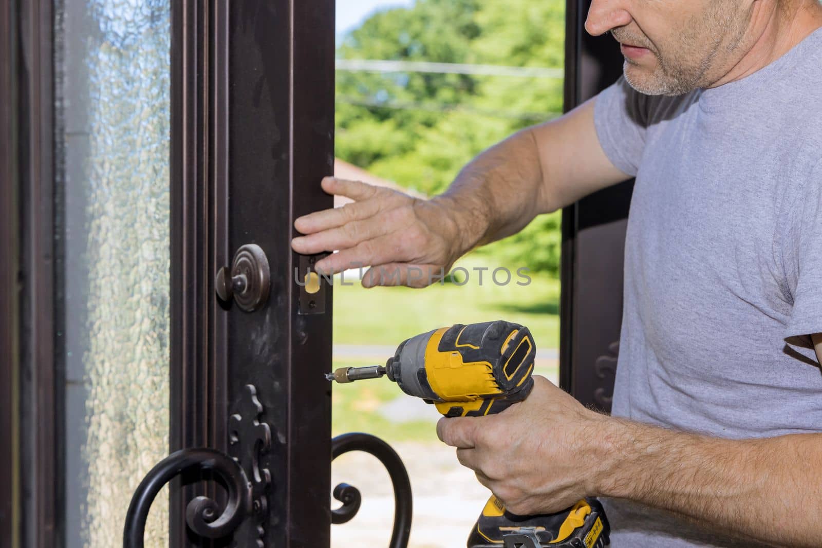 Carpenter worker installing lock on entrance door of new home