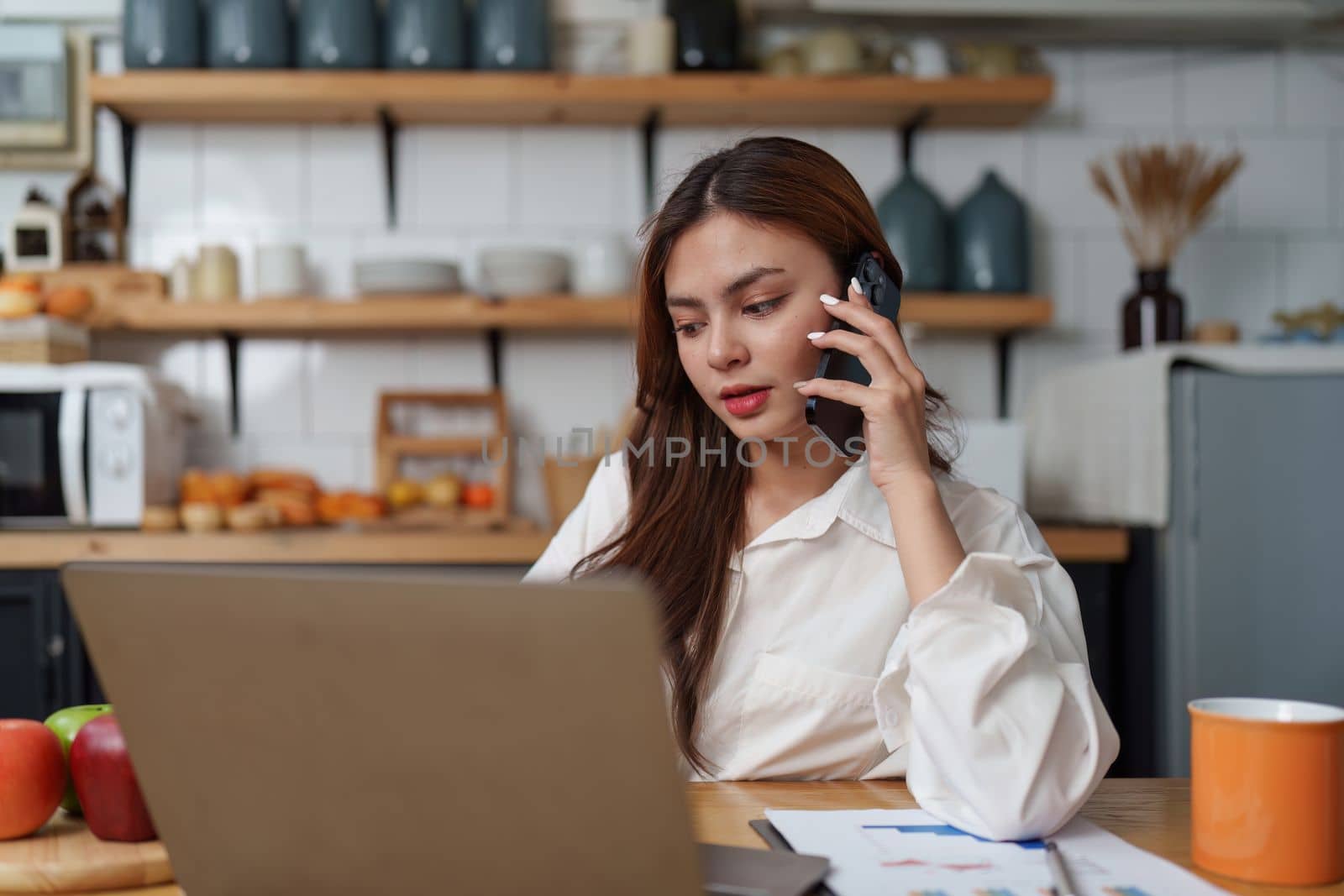 Asian Business woman working at kitchen room at home office and analyze financial report document. Accounting and Finance concept. by itchaznong