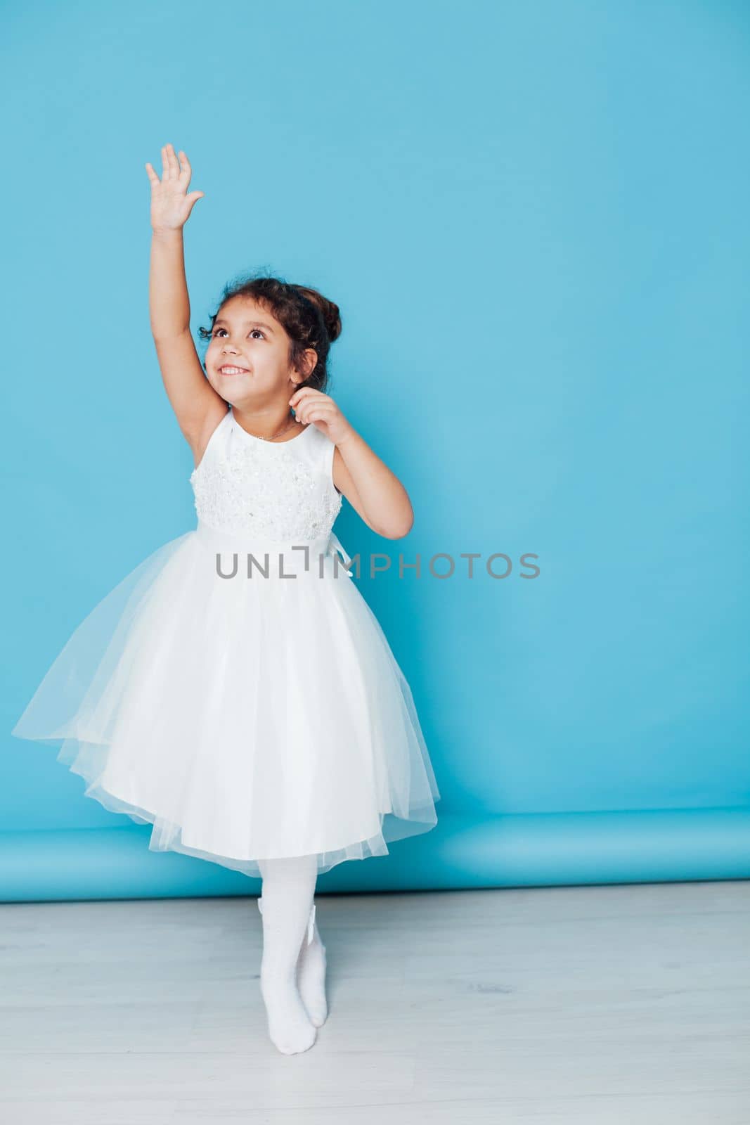 little girl in white dress ballerina dancing on a blue background by Simakov