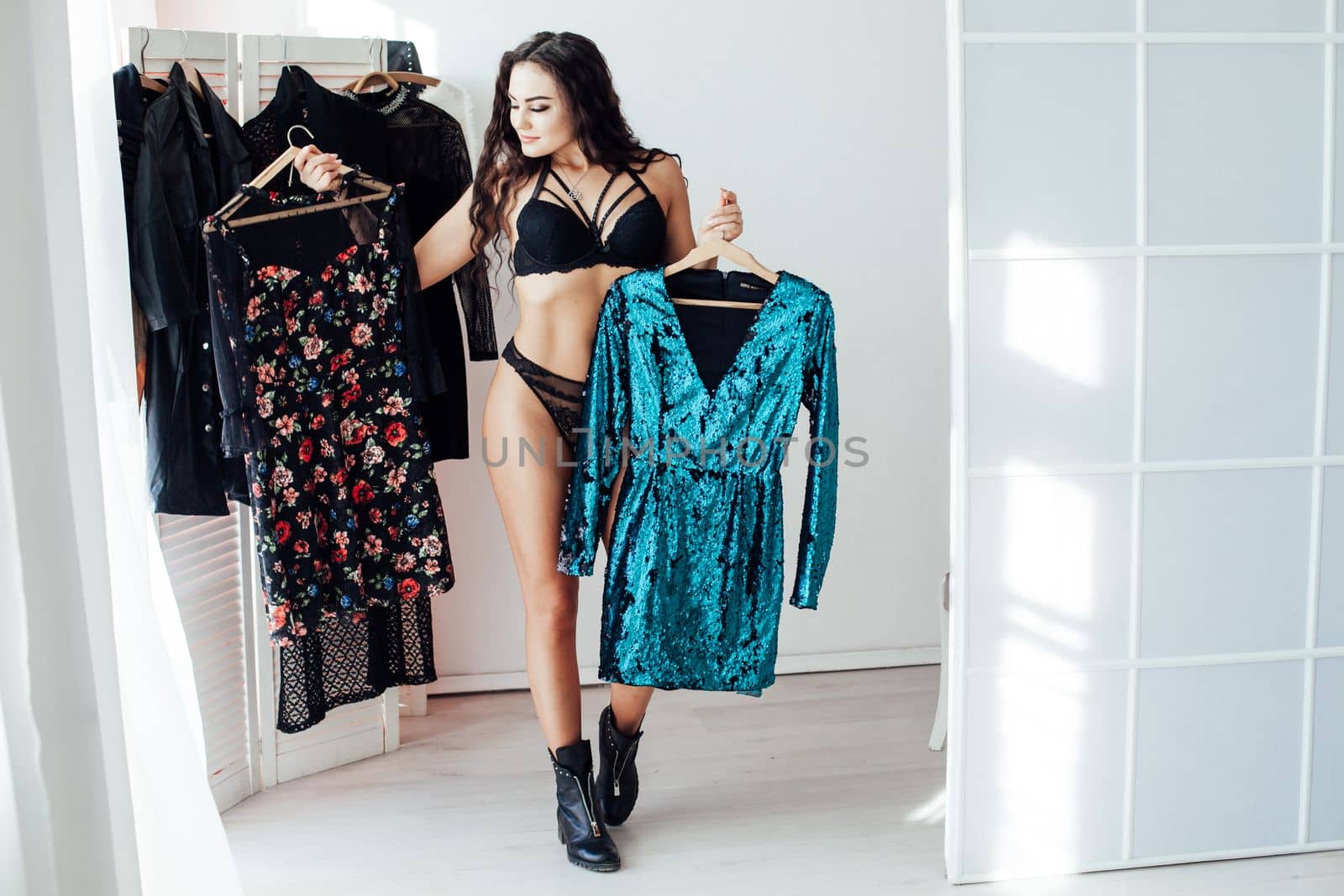 woman in black underwear stands with clothes in the wardrobe of a clothing store