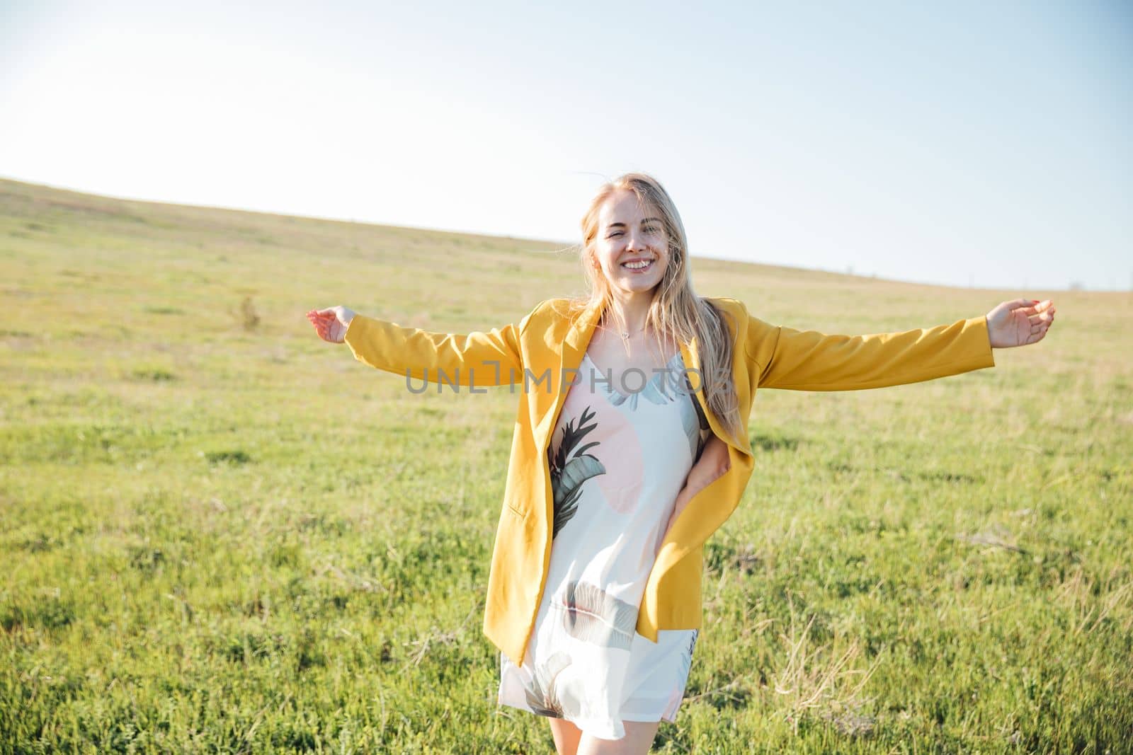 a beautiful blonde in a yellow jacket in nature green glade