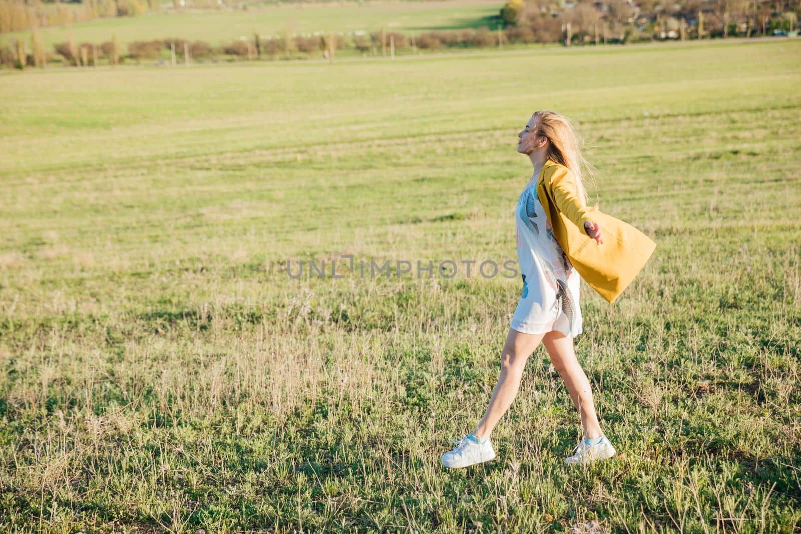 blonde woman walks on green grass in a clearing