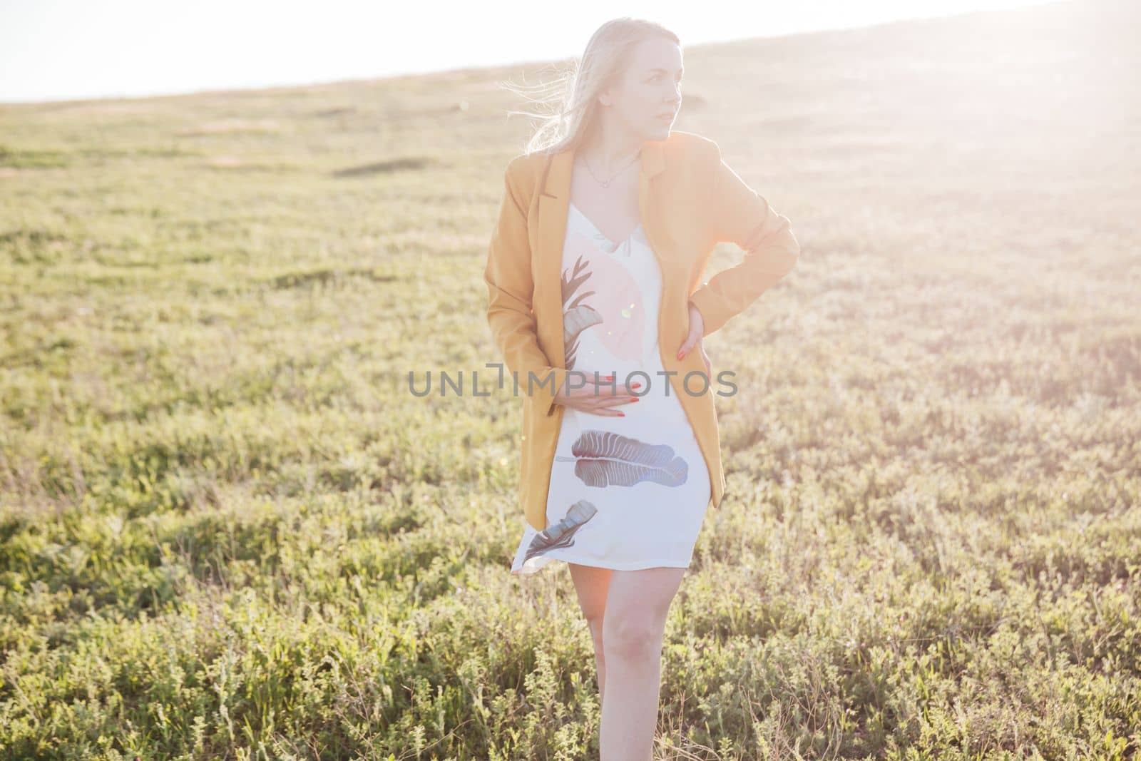 beautiful blonde woman in a green clearing under the rays of the sun