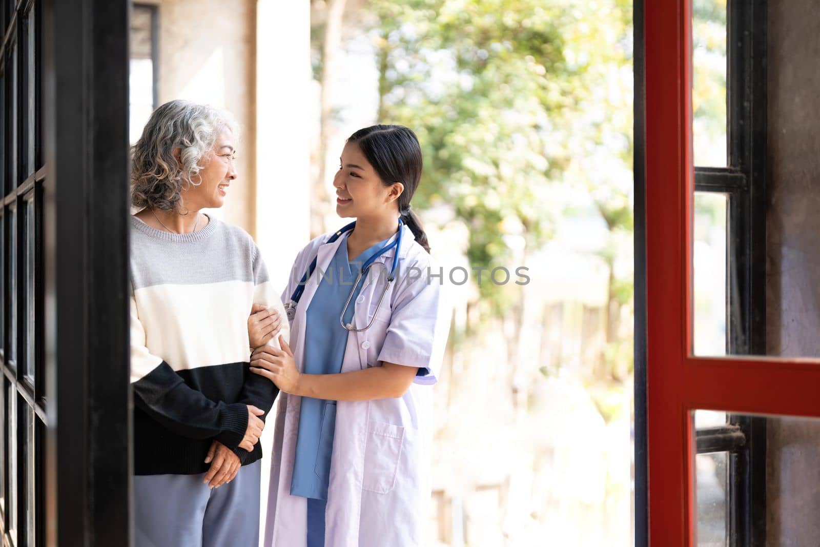 Young caregiver helping senior woman walking. Nurse assisting her old woman patient at nursing home. Senior woman with walking stick being helped by nurse at home..