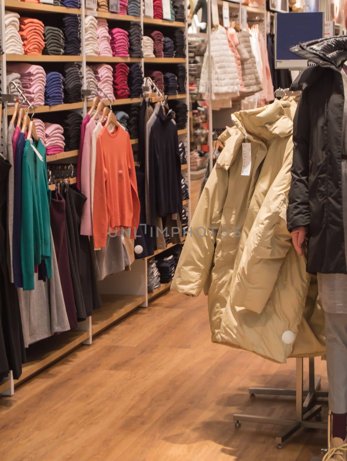 A colorful collection of women's autumn and winter clothing hangs on a hanger in the store.