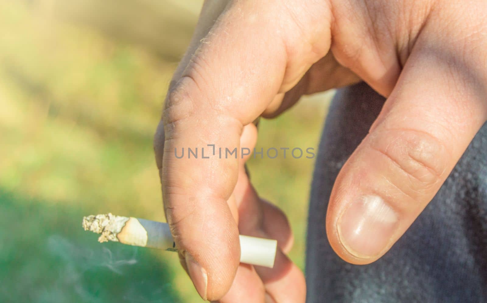 Close-up of an elderly man's hand Smoking a cigarette, outdoors, on a summer day by claire_lucia
