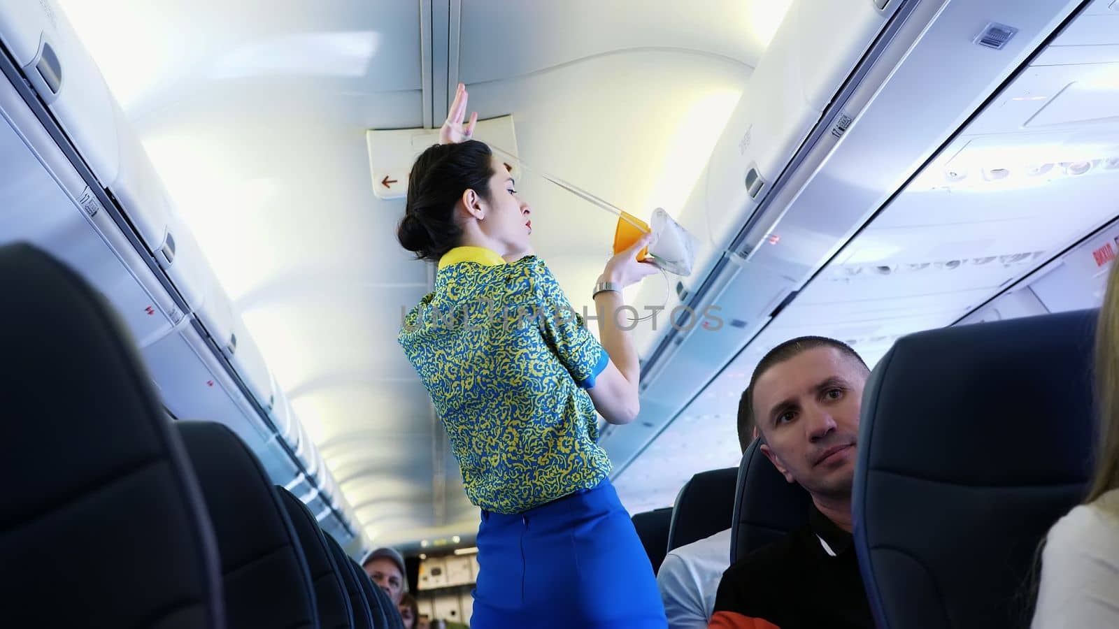 AIRPORT BORYSPIL, UKRAINE - OCTOBER 24, 2018: Ukraine International Airlines. Flight attendant, stewardess gives preflight instructions, during Pre-flight safety demonstration. Interior of airplane with passengers on seats by djtreneryay