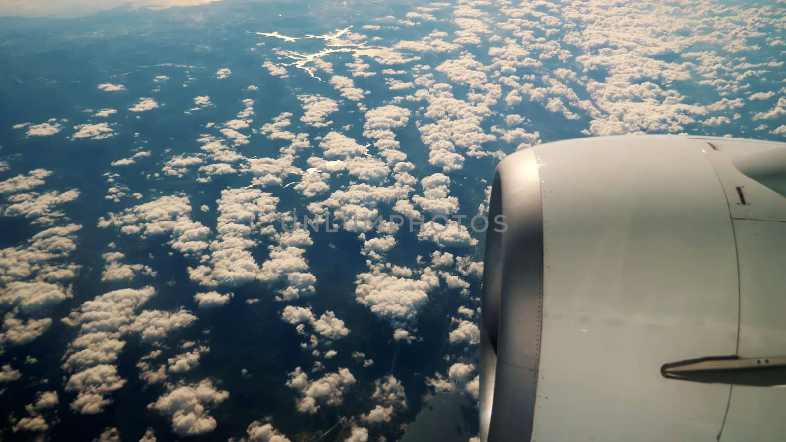 Blue Sky and white fluffy Clouds View from above through airplane's window at sunrise. High quality photo