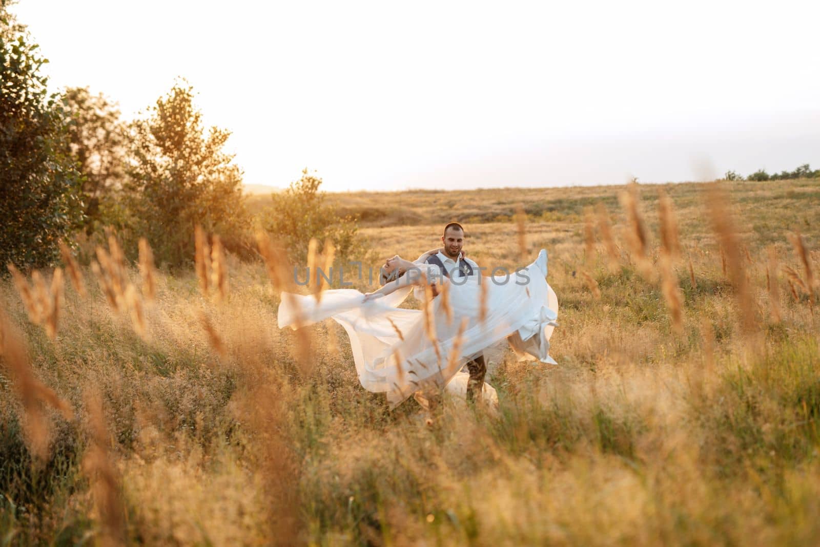 bride blonde girl and groom in a field at sunset light