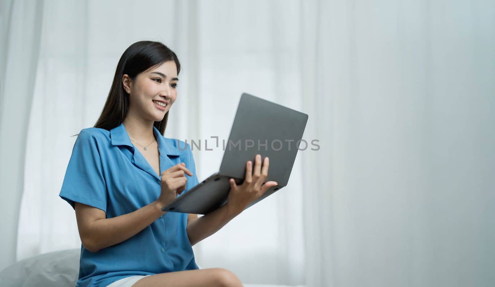 Happy, Relaxing Young beautiful Asian female watching movie or series on notebook in emotional smile happily while laying on the bed in her bedroom. Day off, Chill out and leisure concept. by wichayada