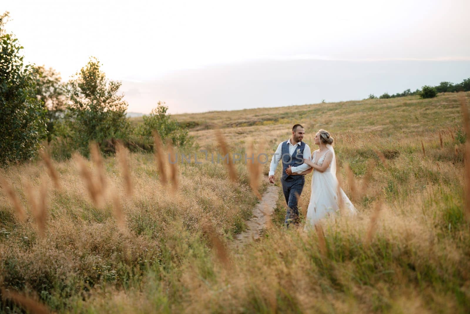 bride blonde girl and groom in a field at sunset light