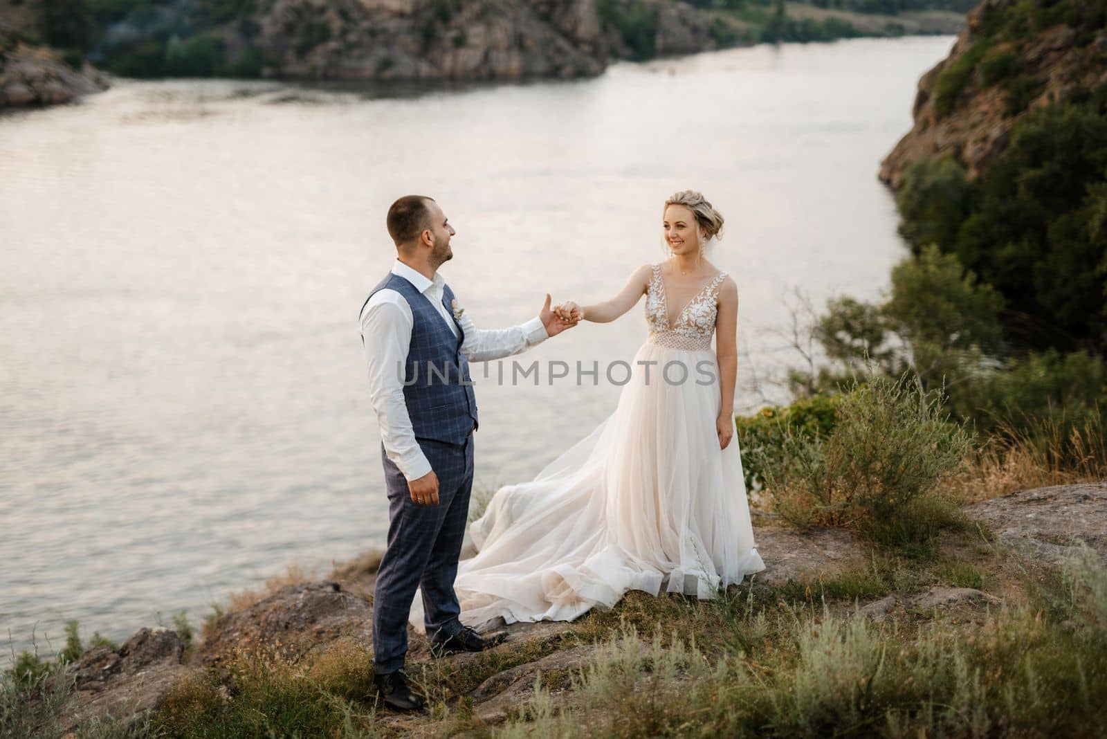 bride blonde girl and groom near the river at sunset light