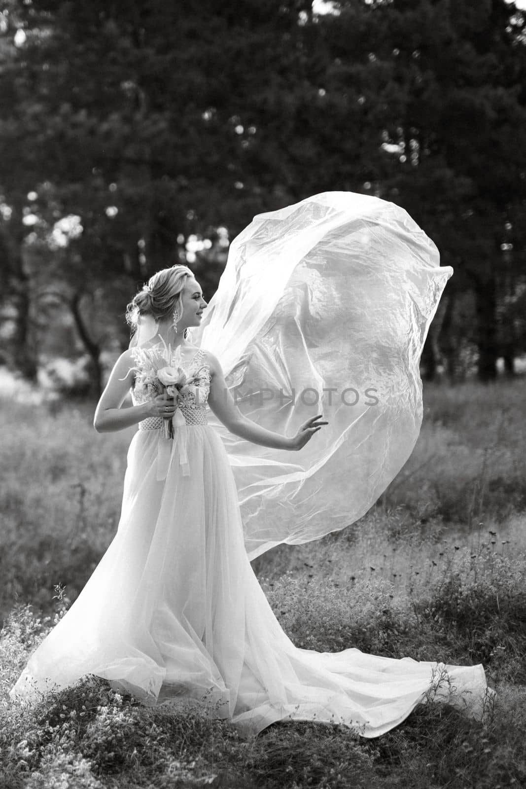 bride blonde girl with a bouquet in the forest in the sunset light