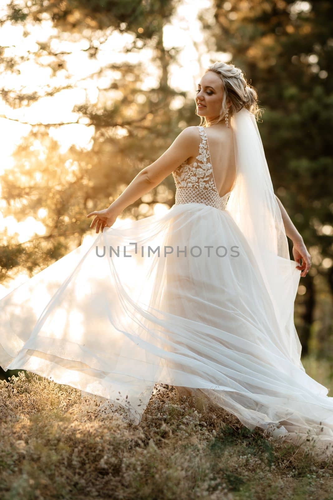 bride blonde girl with a bouquet in the forest in the sunset light