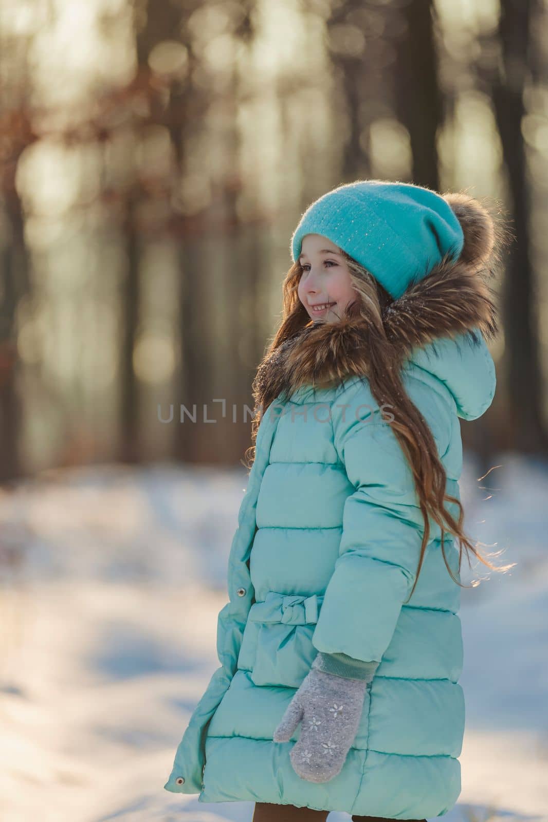 girl in a turquoise squat and a hat in a winter forest, shot vertically