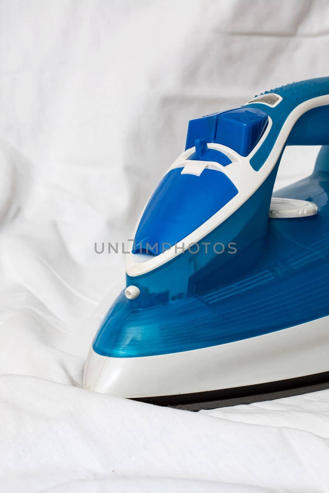 Blue iron on a white sheet, ironing, copy space