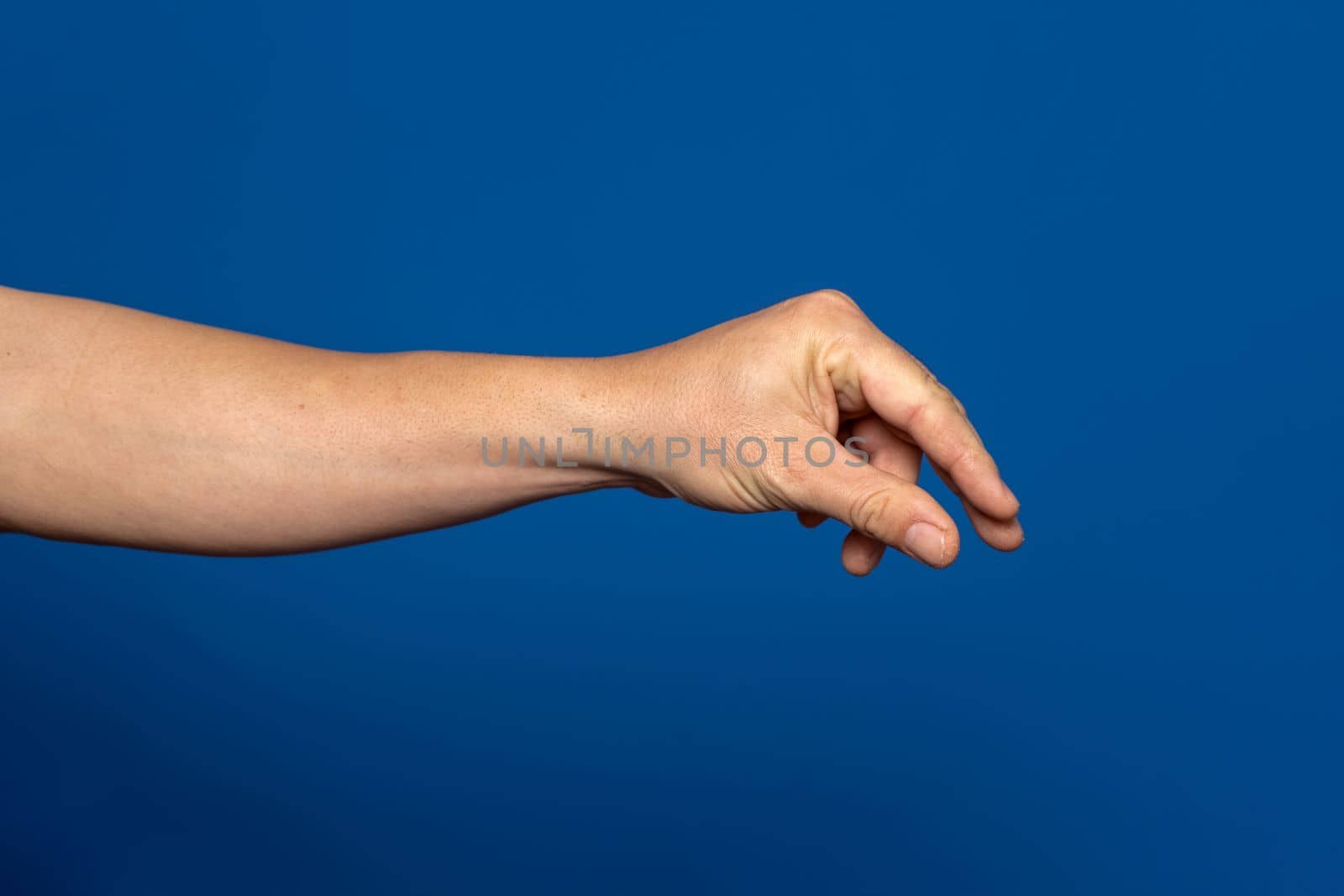 Man hand stretches out to take, arm body part of people isolated on blue background.