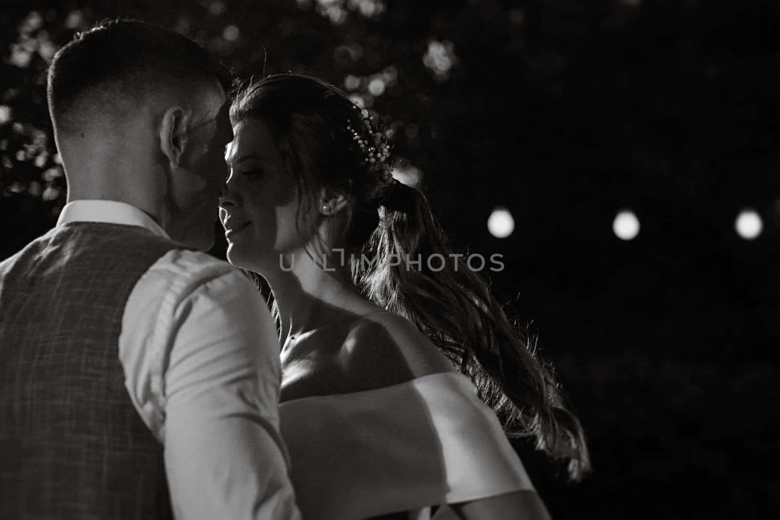 the first wedding dance of the bride and groom inside the restaurant hall in sunset light