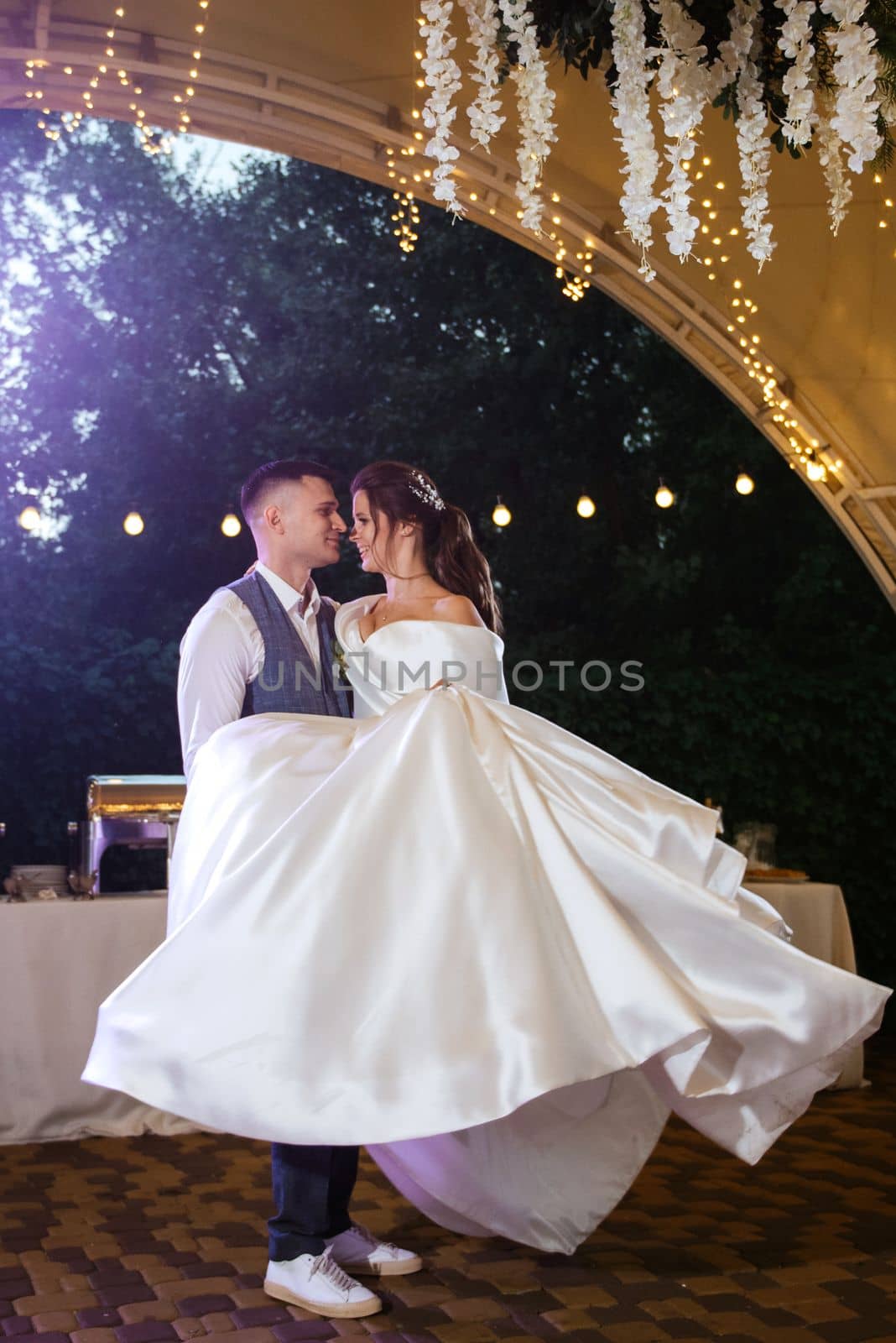 the first wedding dance of the bride and groom inside the restaurant hall in sunset light