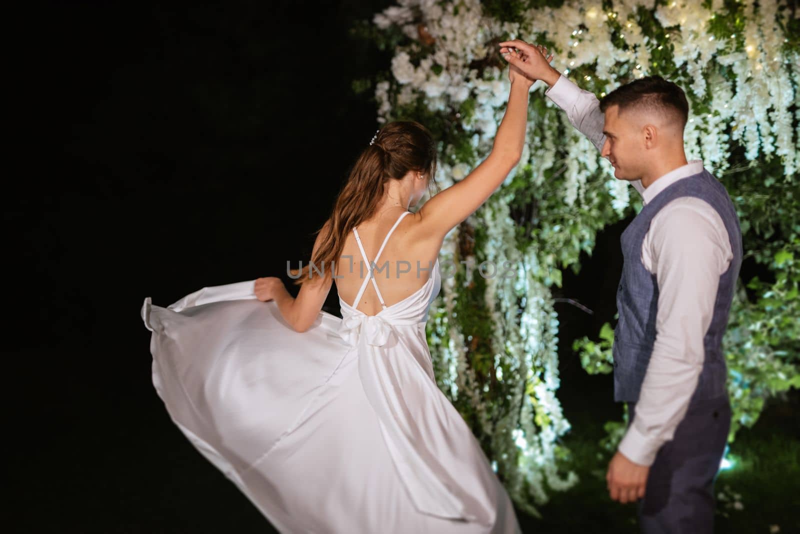 young couple of newlyweds on the evening illuminated arch