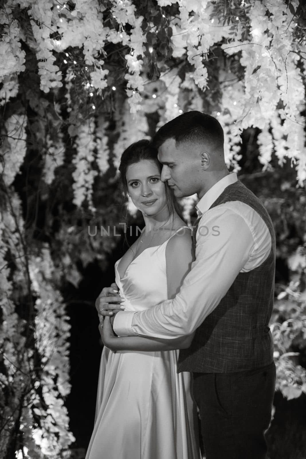 young couple of newlyweds on the evening illuminated arch