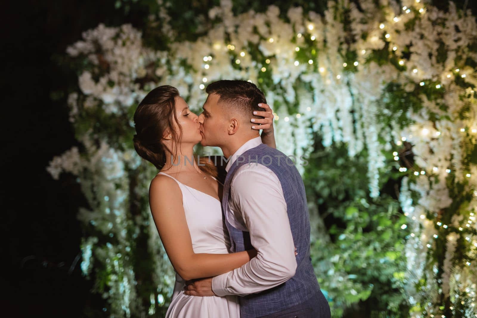 young couple of newlyweds on the evening illuminated arch